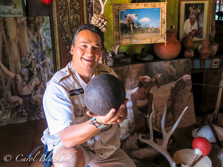 Man holding ball in front of picture of ancient ball game